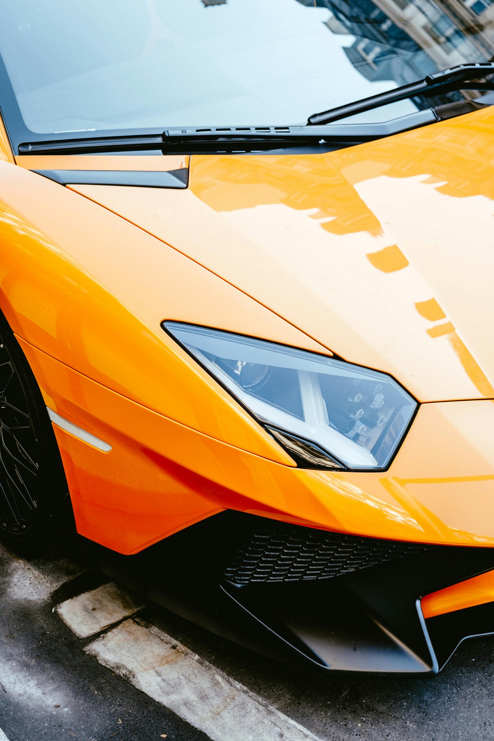 Close-up view of an orange Lamborghini Aventador headlight, showcasing the sleek design and luxury appeal of the supercar.